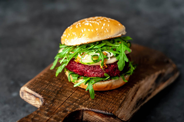 вегетарианский бургер со свеклой, горохом, грушей, рукколой, огурцом на разделочной доске на каменном фоне
 - Фото, изображение