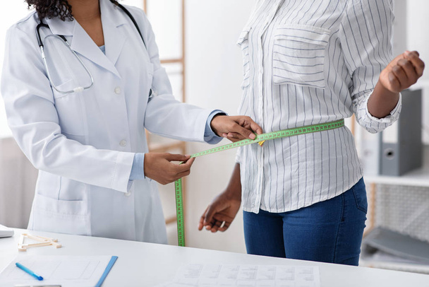 Nutritionniste afro femme mesurant la taille des patients en clinique
 - Photo, image
