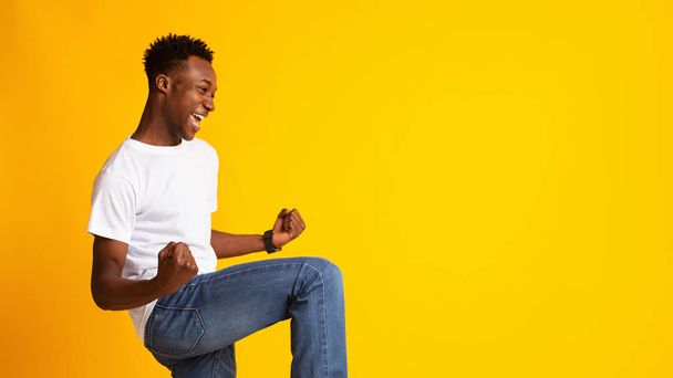 Excited young african man expressing success on yellow - 写真・画像