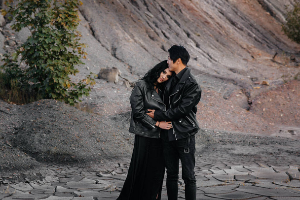 An Asian couple in love in black leather clothes walk in nature among the trees. Style, fashion, love - Fotoğraf, Görsel