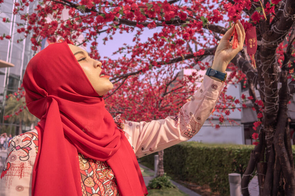 Ισλαμικές γυναίκες θαυμάζουν την ομορφιά των ανθών κερασιάς που δημιουργήθηκαν για να διακοσμήσουν κατά τη διάρκεια του φεστιβάλ. - Φωτογραφία, εικόνα