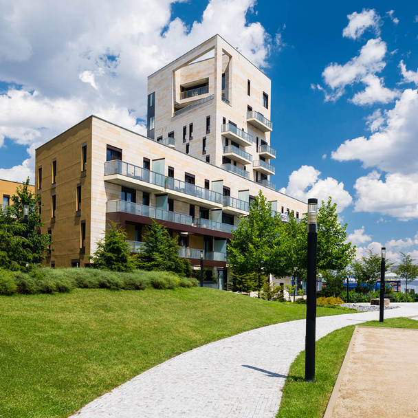 Vista al pubblico di appartamenti contemporanei in zona verde con cielo blu e nuvole bianche sopra
 - Foto, immagini
