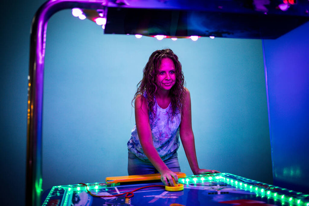 Young woman plays air hockey in an entertainment center - Zdjęcie, obraz