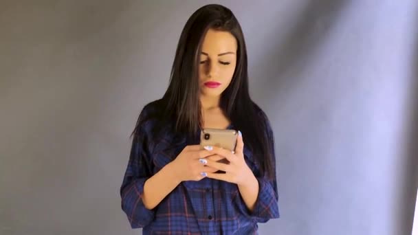 beautiful sexy young girl with black hair texting on phone and smiling - Video