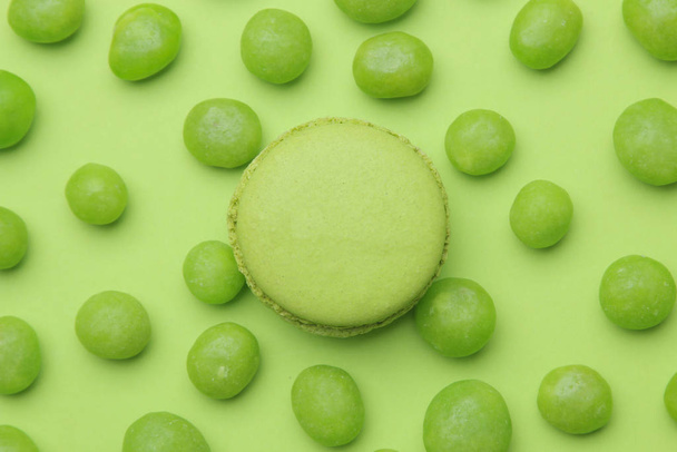 Het concept van minimalisme. Macaroon cake en smakelijke helder groene snoepjes op een heldergroene achtergrond. bovenaanzicht - Foto, afbeelding