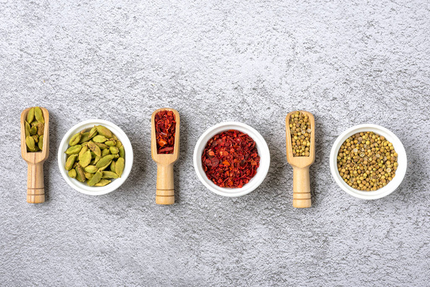 mix of aromatic spices coriander, bergamot, paprika in white cups on a gray concrete background Top view Flat lay Healthy food. - Photo, Image