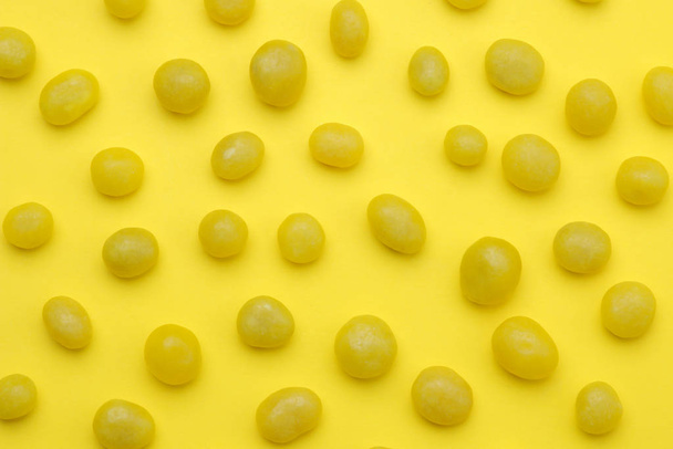 Das Konzept des Minimalismus. Hintergrund von köstlichen leuchtend gelben Bonbons auf leuchtend gelbem Hintergrund. Ansicht von oben. - Foto, Bild