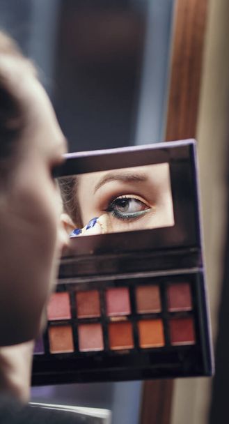 reflection of a female eye in a palette mirror with multi-colored shadows, girl doing makeup indoors, morning routine, the concept of beauty and cosmetics - Φωτογραφία, εικόνα