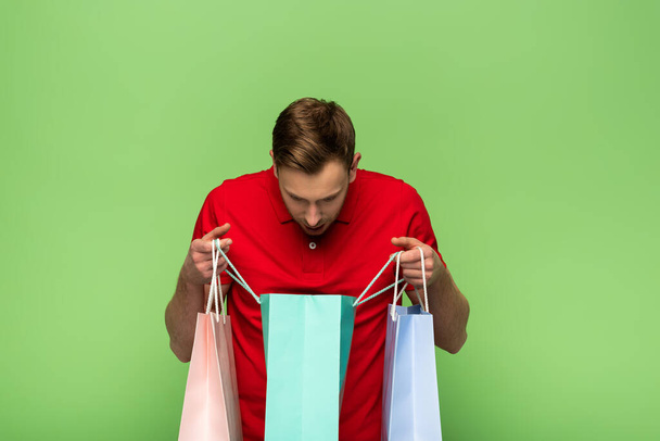 man looking in shopping bags isolated on green - Φωτογραφία, εικόνα
