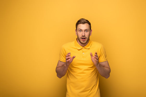 shocked handsome man in yellow outfit gesturing on yellow background - Foto, Imagen