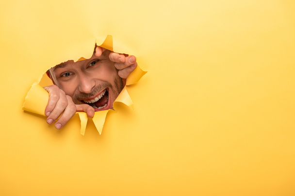 возбужденный красавец, выглядывающий через желтую бумажную дыру
  - Фото, изображение
