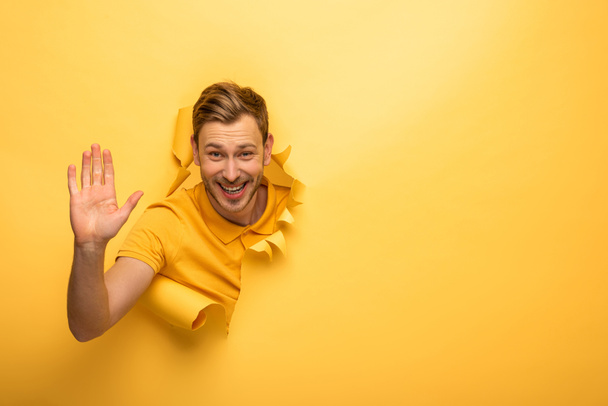 homem bonito feliz em roupa amarela no buraco de papel amarelo dando alta cinco
 - Foto, Imagem
