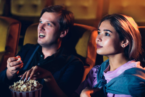 Caucasian lover enjoying to watch movie and eating popcorn together in the cinema - Foto, Imagem
