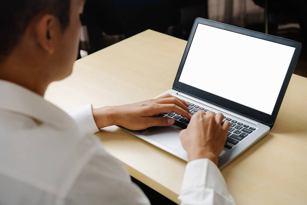 Zakenman of kantoormedewerker die laptop gebruikt terwijl hij achter zijn bureau zit. - Foto, afbeelding