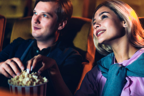 Caucasian lover enjoying to watch movie and eating popcorn together in the cinema - Foto, afbeelding