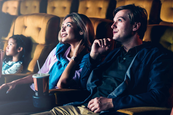 Ένα ζευγάρι και παιδιά απολαμβάνουν και βλέπουν μια ταινία στον κινηματογράφο. - Φωτογραφία, εικόνα