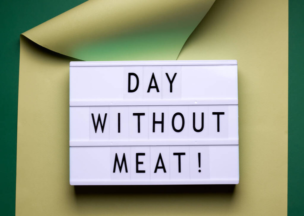 на зеленом фоне находится светильник с завернутым в бумагу текстом. Международный день без мяса
 - Фото, изображение