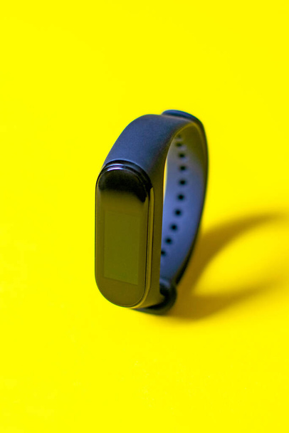 Classic blue fitness tracker on yellow background. Fitness bracelet for sports training. - 写真・画像