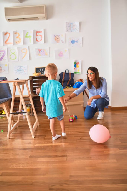 Giovane bambino caucasico che gioca a scuola con l'insegnante. Madre e figlio in sala giochi intorno ai giocattoli
. - Foto, immagini