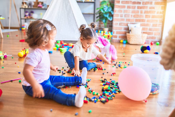 Suloiset pikkulapset leikkivät rakennuspalikoilla lelu päiväkodissa
 - Valokuva, kuva