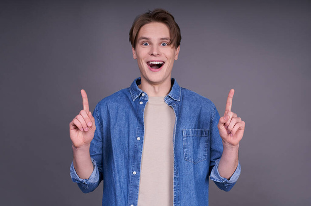 Young cute cute caucasian guy, hipster, fashion man, in a denim shirt. People lifestyle concept. Layout copy space. Raising your thumbs up, showing approval, is cool. Copy space. - Φωτογραφία, εικόνα
