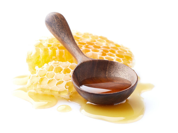 Honeycomb with honey drop and wooden spoon in closeup - Foto, afbeelding