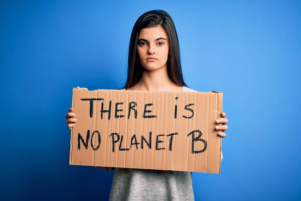 Молода красива жінка-активістка брюнетка тримає прапор, що протестує, щоб піклуватися про планету з впевненим виразом на розумне обличчя думаючи серйозно
 - Фото, зображення