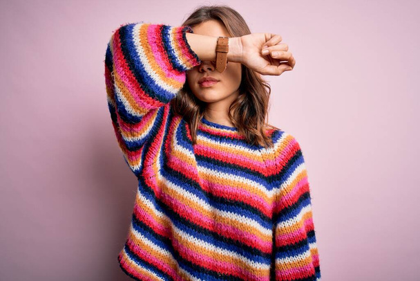 Young beautiful blonde girl wearing glasses and casual sweater over pink isolated background covering eyes with arm, looking serious and sad. Sightless, hiding and rejection concept - Photo, Image