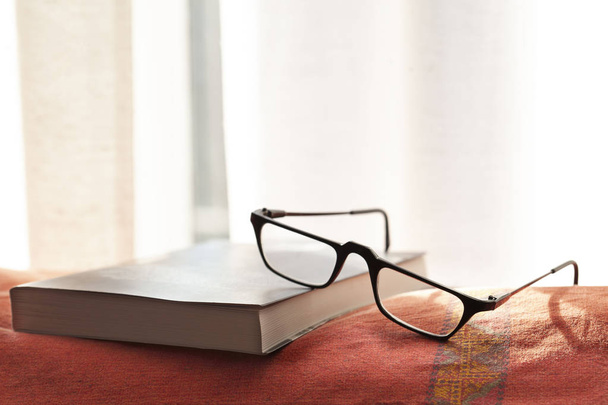 Kitap ve gözlük, metin için fotokopi alanı olan bir koltukta dinleniyor. - Fotoğraf, Görsel