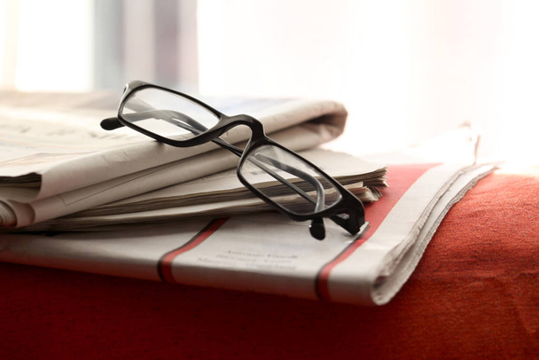 新聞や眼鏡は赤いソファの上に置かれテキストのコピースペースがあります - 写真・画像