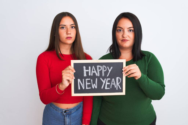 Beautiful women holding blackboard happy new year message over isolated white background with a confident expression on smart face thinking serious - Φωτογραφία, εικόνα