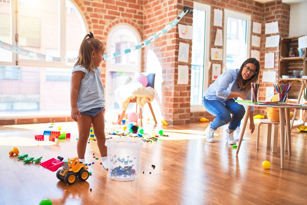 白人の女の子の子供は女教師と遊び場で遊んで学びます.母と娘-おもちゃの周りにプレイルーム - 写真・画像