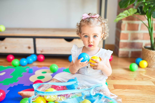 Hermoso bebé caucásico jugando con juguetes en la colorida sala de juegos. Felices y juguetonas bolas coloridas de crecimiento en el jardín de infancia
. - Foto, Imagen