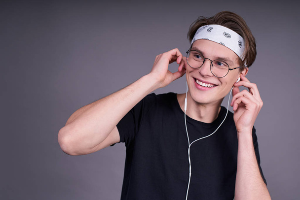 Cute smiling guy wearing headphones over gray background. A man listens to modern music. Modern technologies. Contemporary and contemporary music. Hobbies leisure. - Foto, Imagen