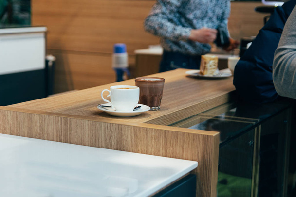 a cup of coffee and hot chocolate are on the table in a cafe,the client is going to pick them up - Fotoğraf, Görsel