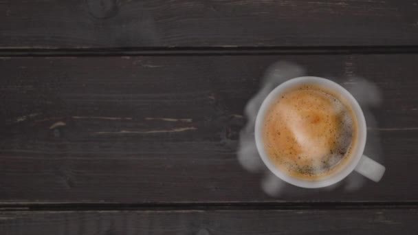 熱いコーヒーから蒸気のトリクルが立ち上がる。古い木製のテーブルの上に熱いコーヒーカップ。ビジネスと飲料の概念. - 映像、動画