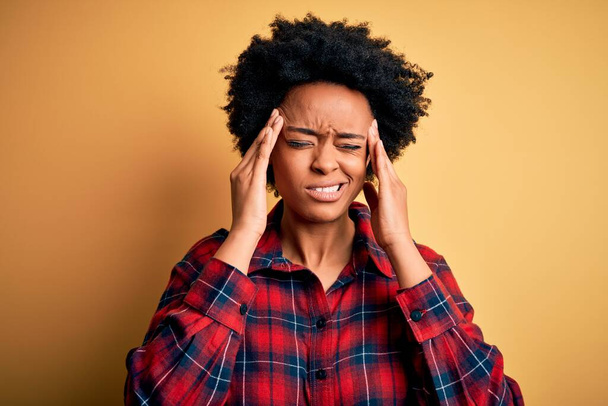 Fiatal gyönyörű afro nő göndör haj visel alkalmi ing szenved fejfájás kétségbeesett és hangsúlyozta, mert a fájdalom és a migrén. Kezeket a fejre!. - Fotó, kép