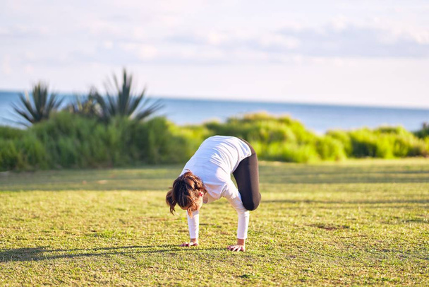 Giovane bella sportwoman praticare yoga. Coach insegnamento corvo posa al parco
 - Foto, immagini