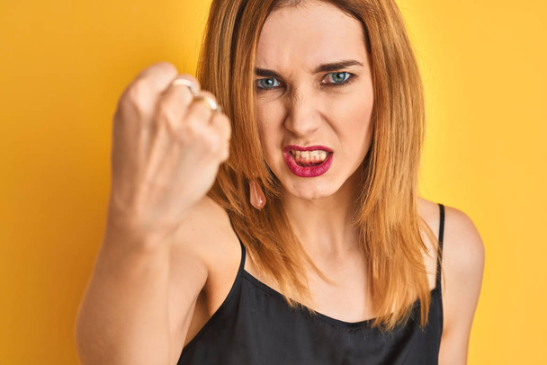 Kafkasyalı zarif bir kadının, izole edilmiş sarı arka planda kızgın ve sinirli bir şekilde bağırması, çıldırması ve el kaldırması, öfke konsepti. - Fotoğraf, Görsel