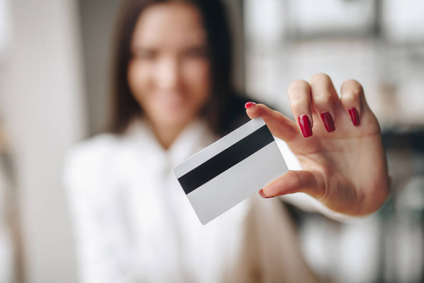 a girl a bank employee holds a credit card in his hand, his face is blurred - Foto, Bild