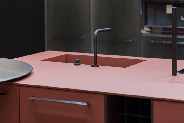 Trendy kitchen of dark red color, one-piece countertop and sink, modern designer kitchen with an island. - Foto, immagini