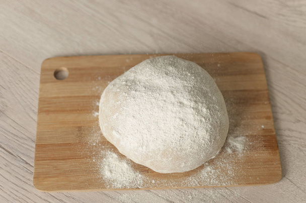 Сире тісто, покрите борошном на дерев'яній обробній дошці ідея рецепту харчової фотографії
  - Фото, зображення
