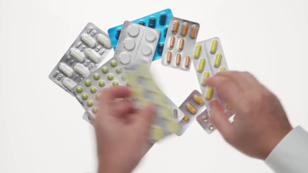 Man hand met pillen, tabletten, vitaminen, drugs, capsules geïsoleerd op witte achtergrond. Wit shirt, zakelijke stijl. Gezondheidszorgconcept. Farmaceutische industrie. Apotheek. - Video