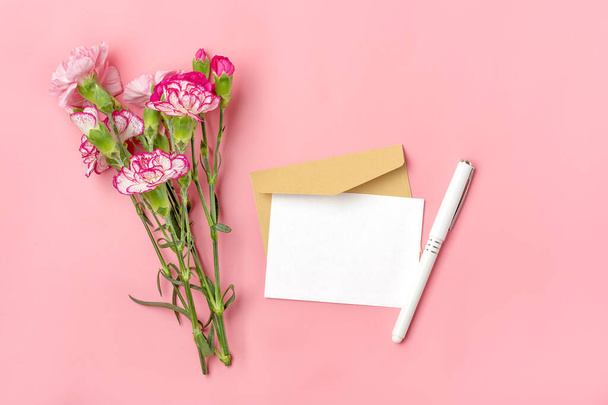 bouquet of pink carnation flower envelope, pen and white note paper on pink background Top view Flat lay Holiday card 8 March, Happy Valentine's day, Mother's, Memorial, Teacher's day concept. - 写真・画像