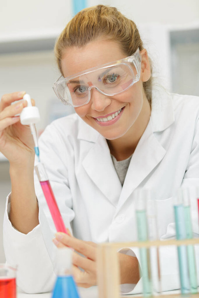 happy woman holding a pipette in a lab - Фото, изображение