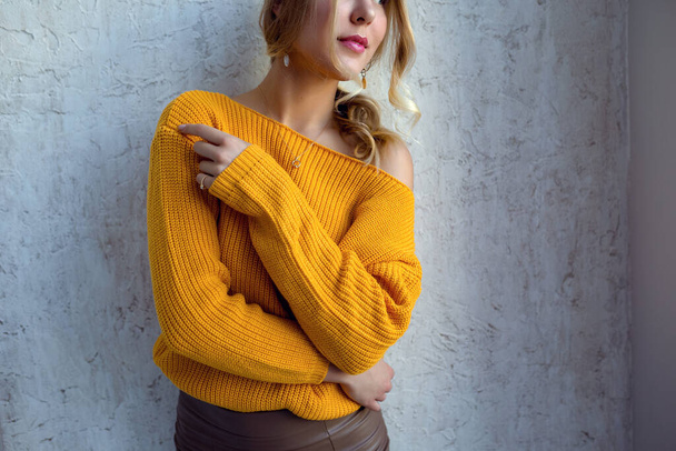 Young woman in a yellow sweater posing against the wall. idea and concept of comfort and tenderness - Zdjęcie, obraz