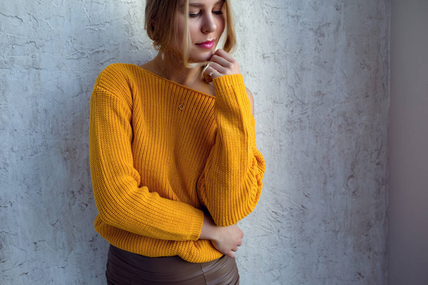 Jeune femme en pull jaune posant contre le mur. idée et concept de confort et de tendresse
 - Photo, image
