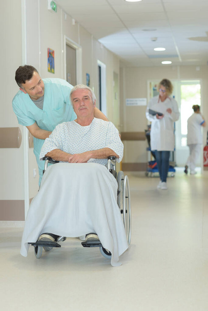 nurse pushing an elderly mans wheelchair - Foto, imagen