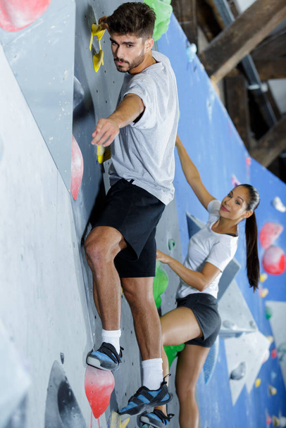 delighted couple climbing up the wall together - 写真・画像