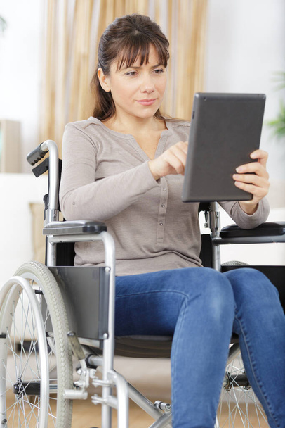 woman in wheelchair working with tablet pc in office - Photo, image